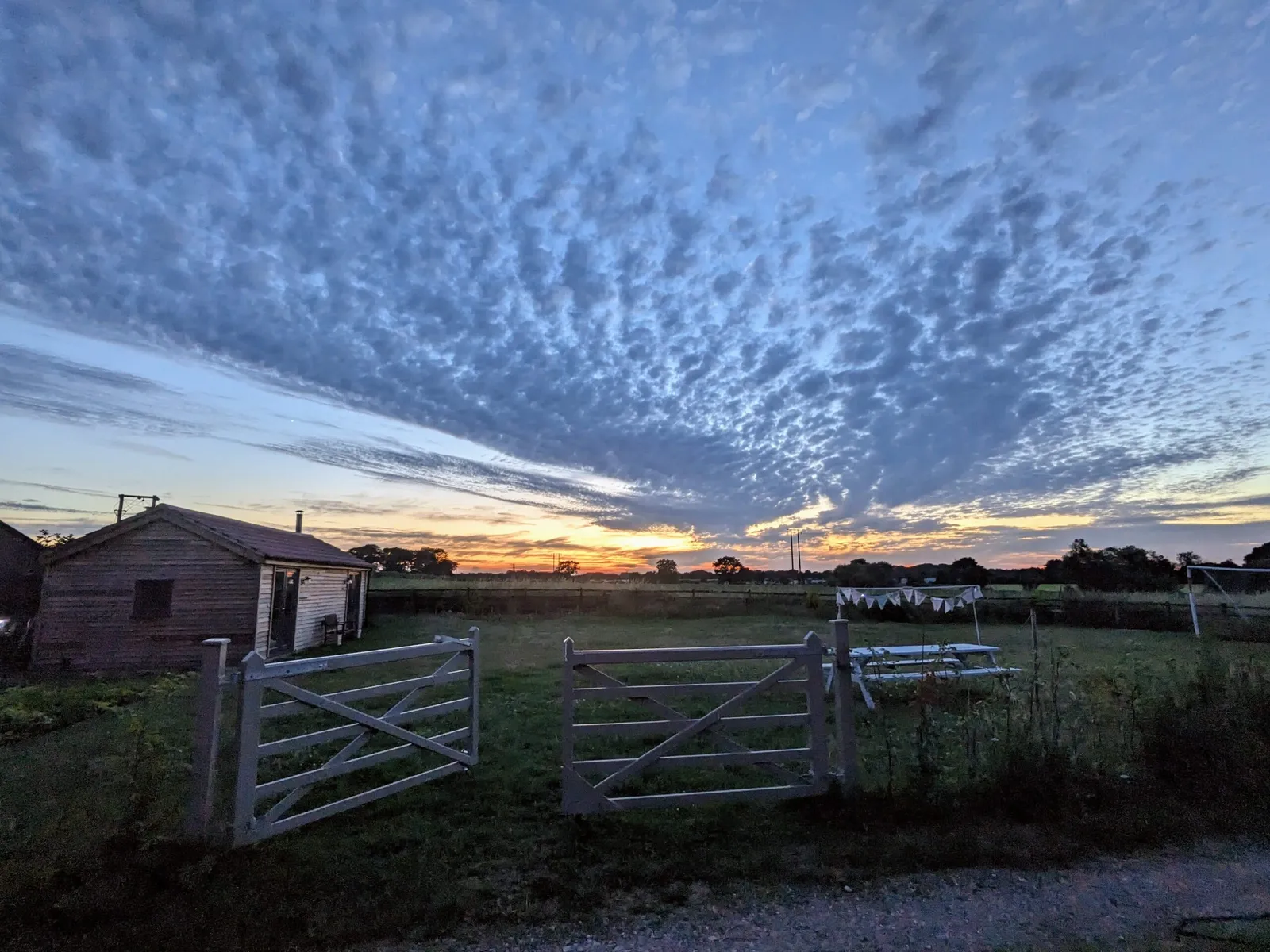 Sunset over farmland. Fence gates in the foreground